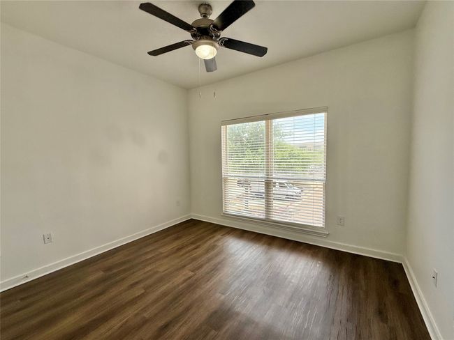 Empty room with baseboards, dark wood-style floors, and a ceiling fan | Image 8