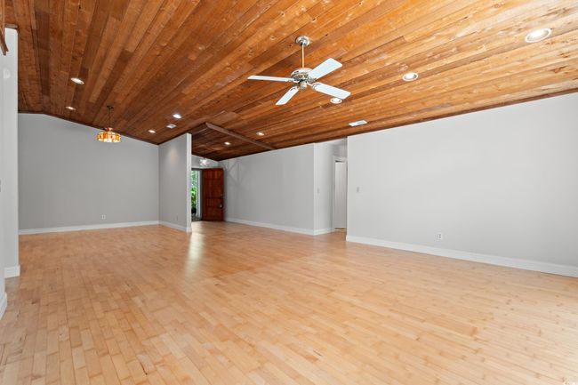 Unfurnished living room featuring light wood-style flooring, wooden ceiling, lofted ceiling, recessed lighting, and ceiling fan | Image 7