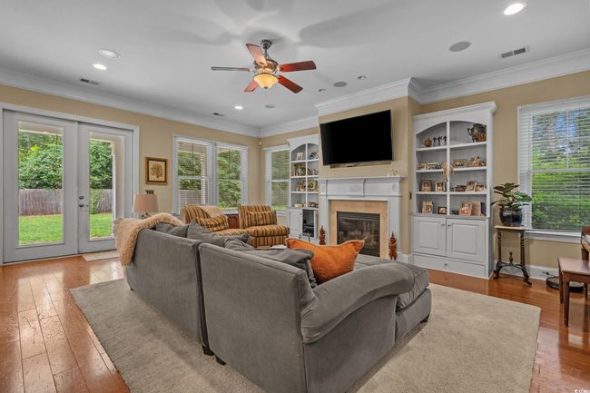 Living area featuring a glass covered fireplace, light wood-style floors, ceiling fan, ornamental molding, and french doors | Image 12
