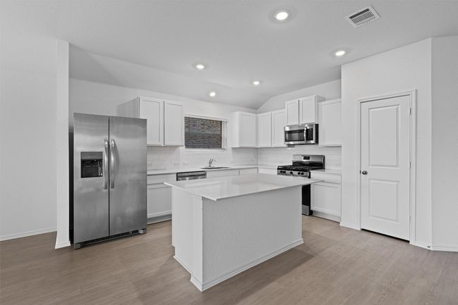Kitchen with stainless steel appliances, backsplash, light wood-style floors, a kitchen island, and vaulted ceiling | Image 4