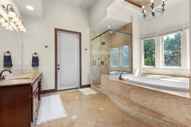 Primary bathroom with a chandelier, vanity, a bath, tile patterned floors, and a shower stall | Image 15