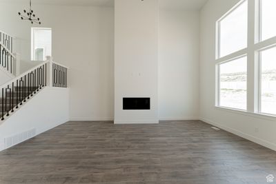 Unfurnished living room with a high ceiling, dark wood-type flooring, and a notable chandelier | Image 3