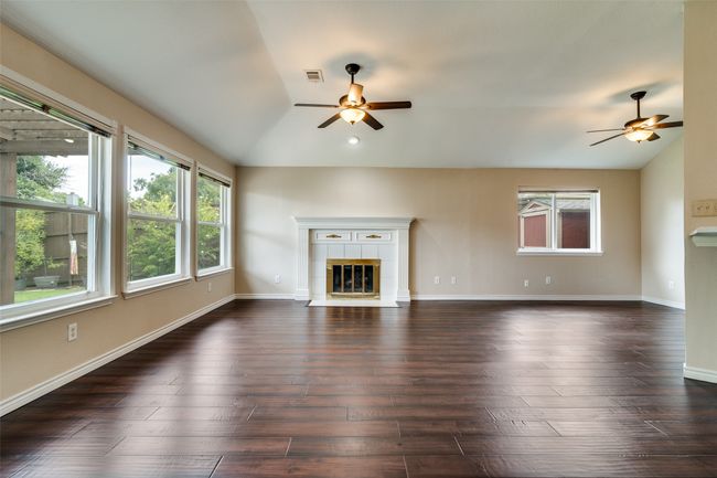 Unfurnished living room featuring a tile fireplace, a ceiling fan, lofted ceiling, and dark wood-style floors | Image 10