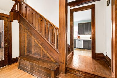 Front Mudroom area with bench, hardwood floors, off to the left is a 1/2 Bath, and access stairs to upper levels | Image 3