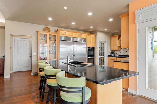 Kitchen featuring dark wood-style floors, recessed lighting, stainless steel appliances, light brown cabinets, and visible vents | Image 15