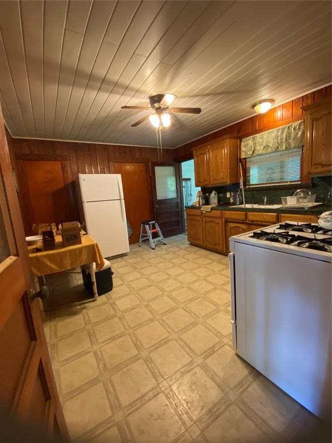 Kitchen featuring fridge, range, wood walls, brown cabinets, and light floors | Image 12