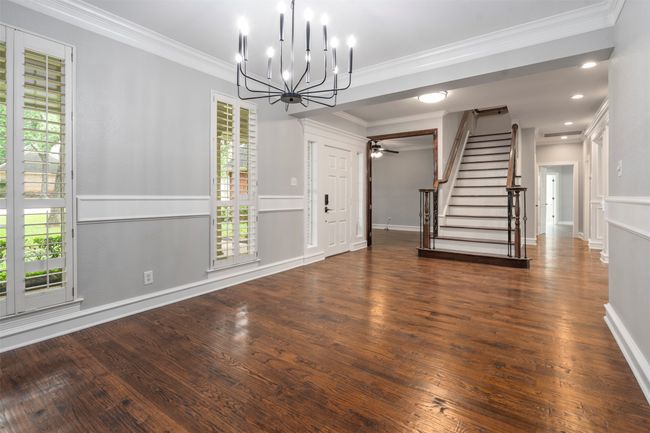 Unfurnished dining area featuring stairway, a chandelier, wood finished floors, ornamental molding, and baseboards | Image 14