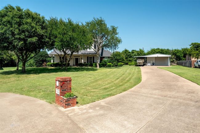 Ranch-style house featuring a front yard, a detached garage, and driveway | Image 21