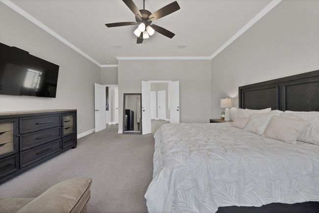 Bedroom featuring light colored carpet, crown molding, baseboards, ceiling fan, and vaulted ceiling | Image 23