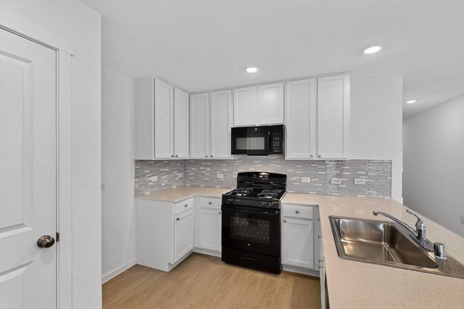 Kitchen featuring black appliances, white cabinetry, light countertops, and recessed lighting | Image 9