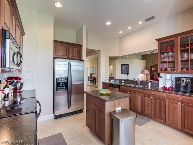 Kitchen with a center island, appliances with stainless steel finishes, backsplash, sink, and light tile flooring | Image 5