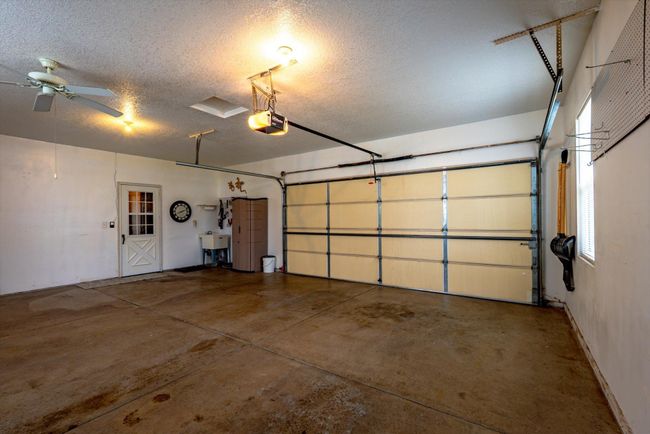 Fully insulated and heated 2-car garage with finished walls and ceiling, a ceiling fan, window for natural light, utility sink near door to the house, and a screen door as well—making it ideal for year-round use. | Image 33
