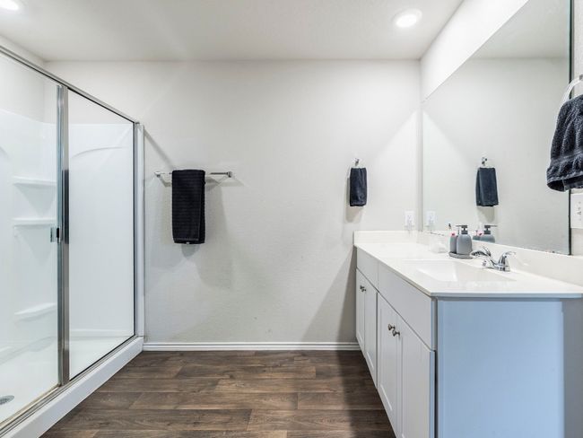 Full bathroom featuring double vanity, a sink, a stall shower, and wood finished floors | Image 18