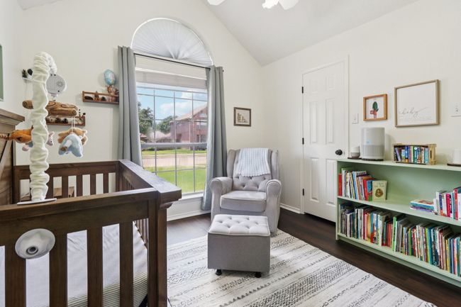 Bedroom with a nursery area, lofted ceiling, wood finished floors, and baseboards | Image 30