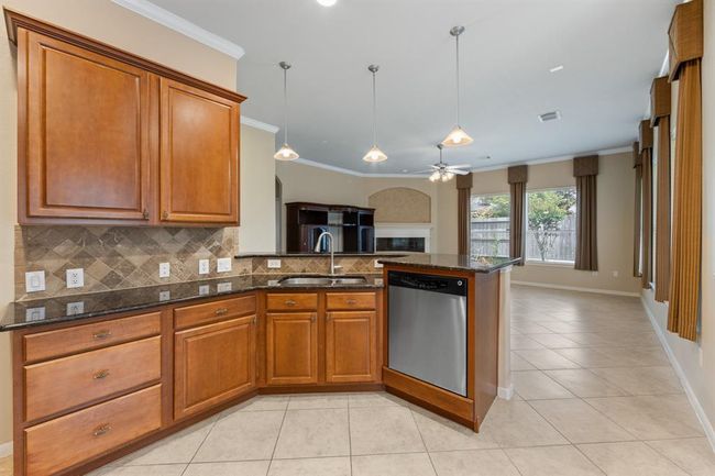 To the right of the entryway is the kitchen, featuring tile floors, crown molding, and sleek granite countertops. | Image 21