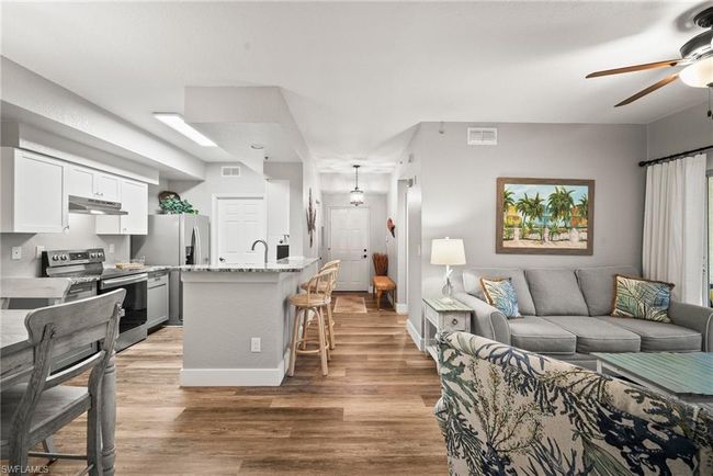 Living room with ceiling fan, visible vents, and light wood-style floors | Image 6