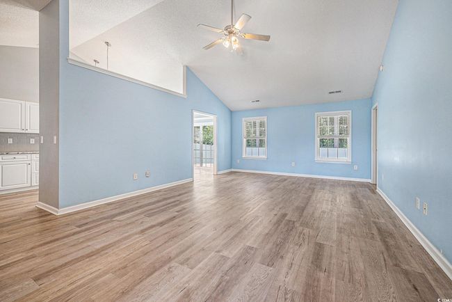 Unfurnished living room with high vaulted ceiling, ceiling fan, and light wood-style floors | Image 7
