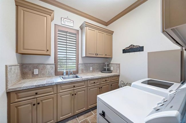 The spacious utility room is designed for both functionality and ease, with ample storage and beautifully tiled counter space...and a waterfront view | Image 18