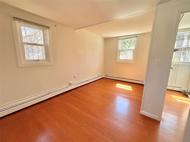 Empty room featuring a baseboard heating unit, hardwood / wood-style floors, baseboards, and baseboard heating | Image 5