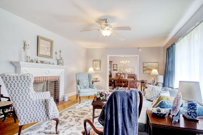 Living room with a fireplace, wood finished floors, ceiling fan, a chandelier, and baseboards | Image 17