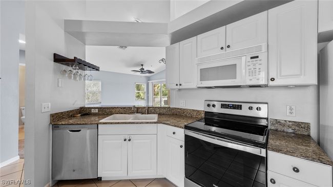 Kitchen featuring stainless steel appliances, white cabinets, a sink, and a ceiling fan | Image 5