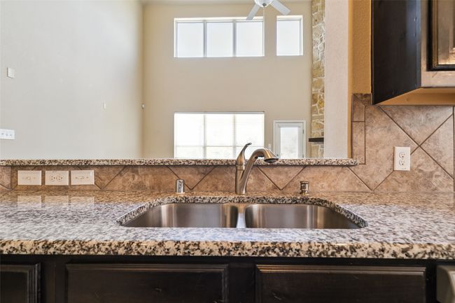 Kitchen with a sink, decorative backsplash, ceiling fan, and light stone countertops | Image 14