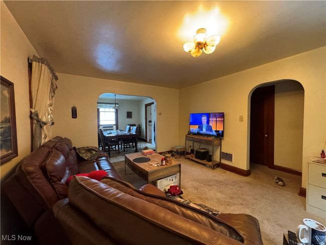 Carpeted living area featuring an inviting chandelier, visible vents, arched walkways, and baseboards | Image 8