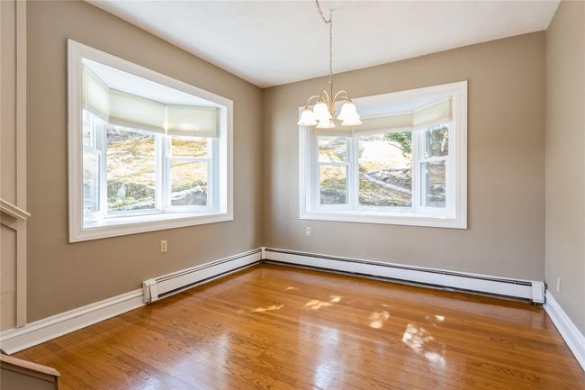The dining room boasts wood floors and 2 bay windows. | Image 9