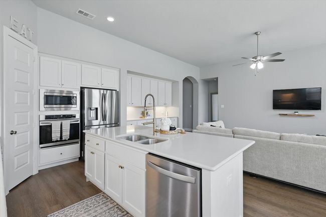 Kitchen with appliances with stainless steel finishes, open floor plan, dark wood finished floors, arched walkways, and light countertops | Image 9