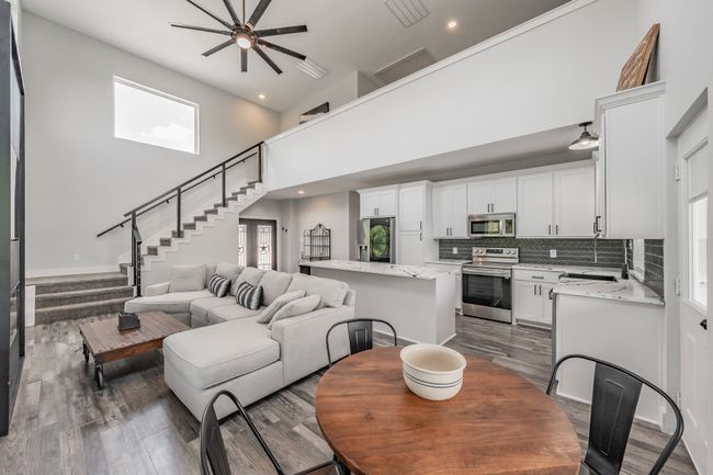 Living area with dark wood-style floors, stairway, ceiling fan, a high ceiling, and recessed lighting | Image 21
