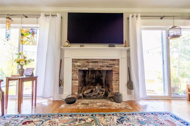 Living area with hardwood / wood-style flooring, a brick fireplace, and crown molding | Image 8