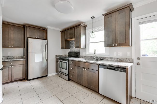 Kitchen featuring stainless steel appliances, ornamental molding, dark brown cabinetry, light stone countertops, and decorative light fixtures | Image 8