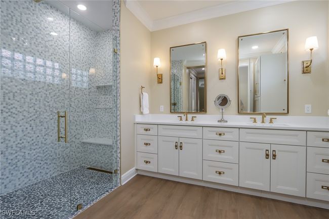 Bathroom featuring a stall shower, crown molding, double vanity, and wood finished floors | Image 11