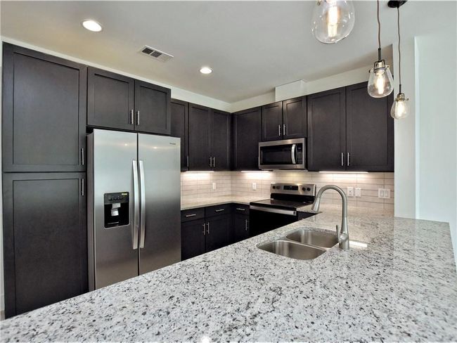 Kitchen with appliances with stainless steel finishes, light stone counters, tasteful backsplash, decorative light fixtures, and recessed lighting | Image 8