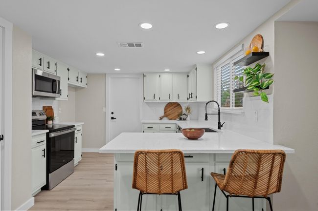 Kitchen with light countertops, stainless steel appliances, a sink, visible vents, and a peninsula | Image 9