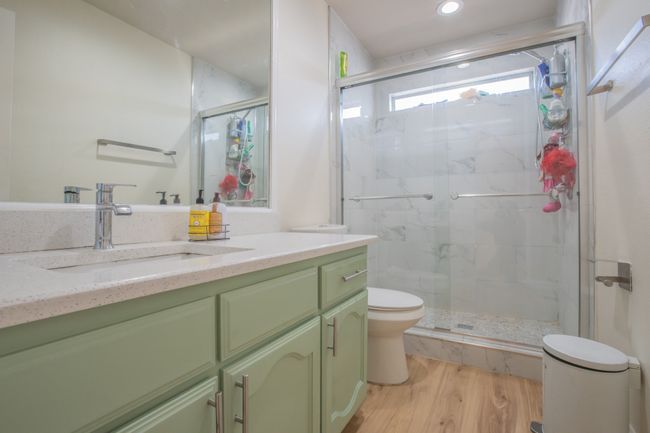 Bathroom featuring wood finished floors, a marble finish shower, vanity, toilet, and recessed lighting | Image 18