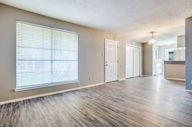 Unfurnished living room with baseboards, a textured ceiling, and wood finished floors | Image 6