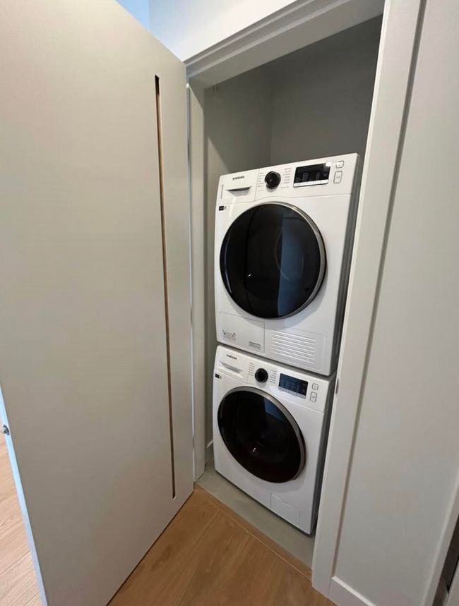 Clothes washing area with light wood-style floors, stacked washer / dryer, and laundry area | Image 9