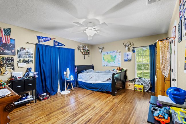 Bedroom featuring ceiling fan, wood finished floors, and a textured ceiling | Image 31