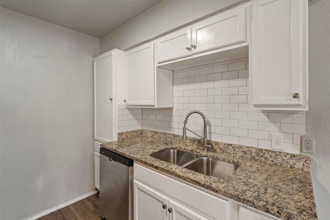 Kitchen with dishwasher, a sink, decorative backsplash, dark wood finished floors, and white cabinetry | Image 13