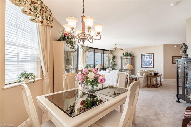 Carpeted dining space with ceiling fan with notable chandelier | Image 25