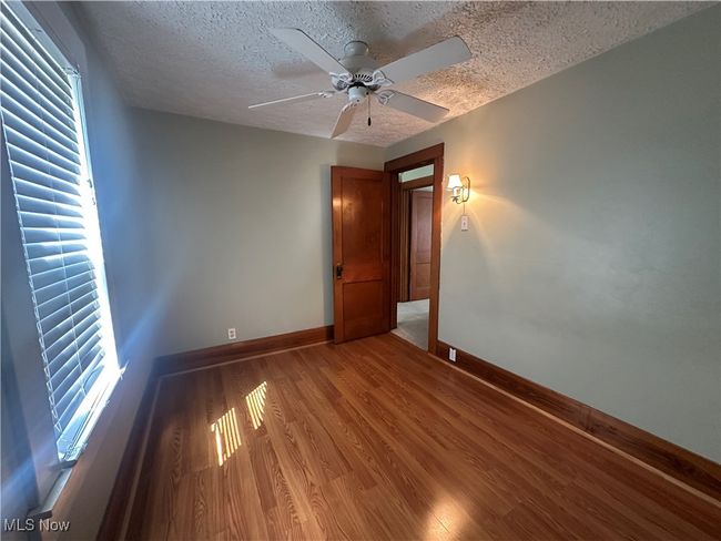 Spare room featuring light wood-type flooring, a textured ceiling, baseboards, and ceiling fan | Image 18