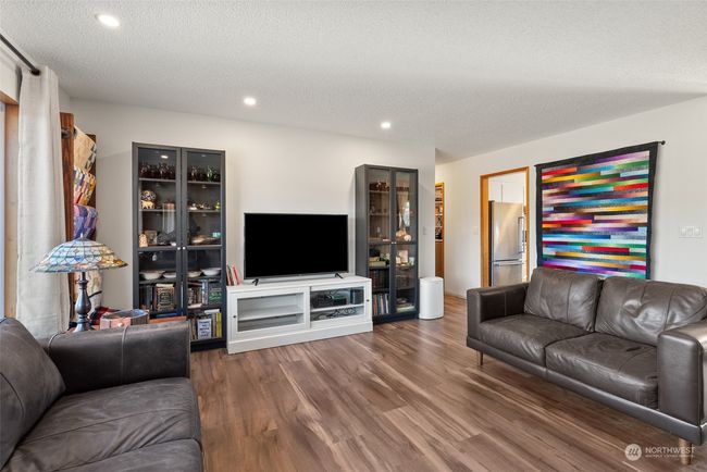The living room offers ample space for a functional and versatile layout, allowing you to design the perfect setup for relaxation and entertainment. The updated easy care flooring adds a touch of warmth, enhancing the room's inviting and cozy atmosphere. | Image 12