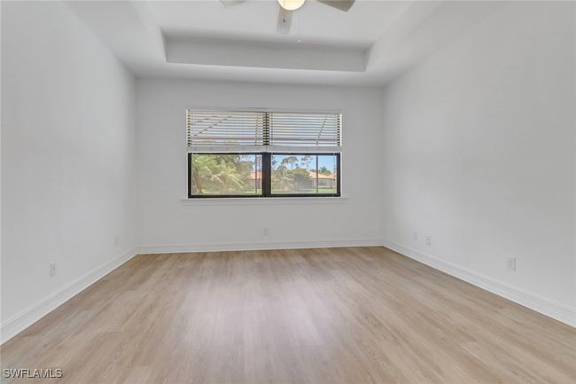 Unfurnished room featuring a tray ceiling, light wood-style floors, a ceiling fan, and baseboards | Image 16