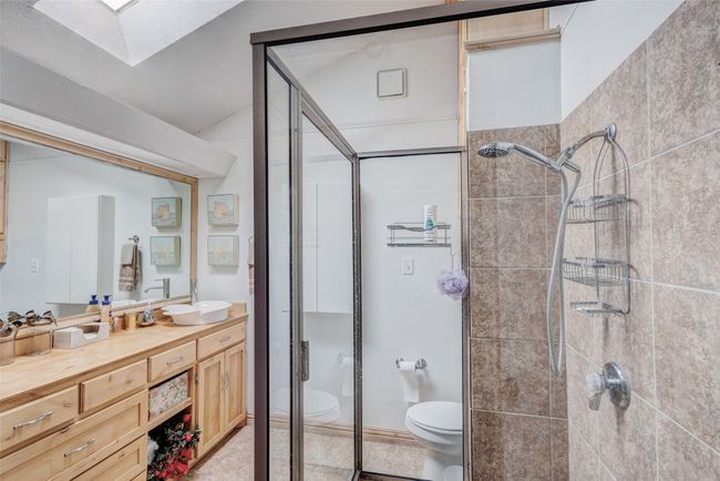 Full bathroom featuring vanity, a skylight, toilet, and a shower stall | Image 8