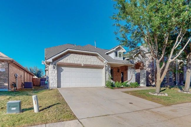 View of front of house featuring an attached garage, a front yard, concrete driveway, stone siding, and roof with shingles | Image 4