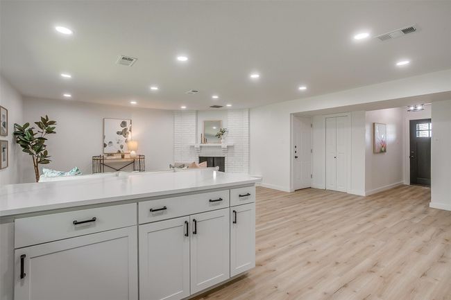 Kitchen featuring light wood-type flooring, light countertops, recessed lighting, a fireplace, and open floor plan | Image 13