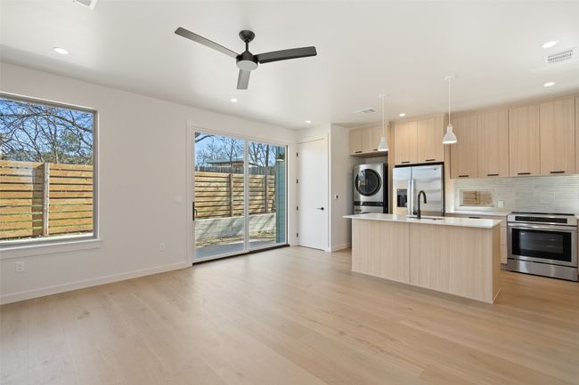 Kitchen featuring visible vents, stacked washer / dryer, modern cabinets, stainless steel appliances, and light brown cabinets | Image 23