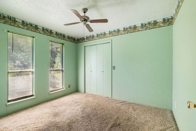 Unfurnished bedroom with carpet flooring, a textured ceiling, a closet, and ceiling fan | Image 10
