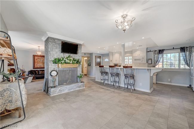 Living room with a chandelier, a large fireplace, and baseboards | Image 44